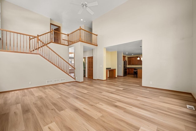 619 Northgate Dr, Sycamore, IL 60178 - unfurnished living room with stairway, light wood finished floors, a ceiling fan, a high ceiling, and recessed lighting