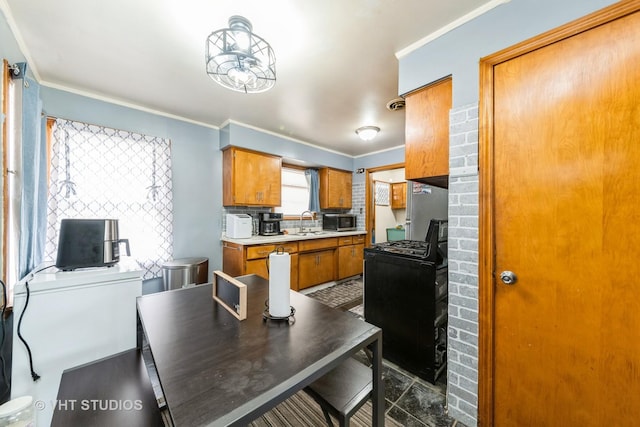 5813 Superior St, Berkeley, IL 60163 - kitchen featuring black range with gas stovetop, stainless steel microwave, brown cabinets, crown molding, and light countertops
