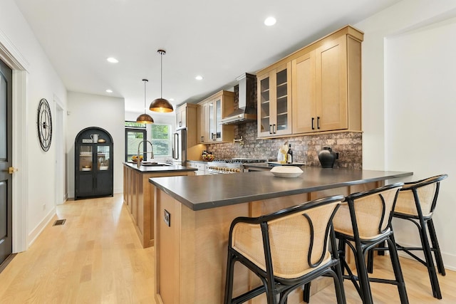 9709 S Leavitt St, Chicago, IL 60643 - kitchen featuring wall chimney range hood, dark countertops, light wood-type flooring, a kitchen island with sink, and backsplash