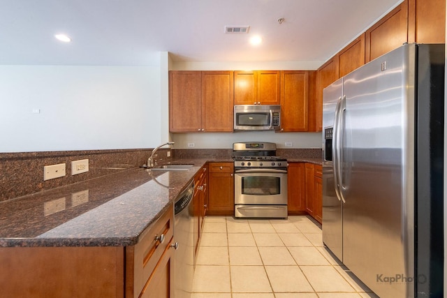 915 S Oak Park Ave Unit 1B, Oak Park, IL 60304 - kitchen featuring appliances with stainless steel finishes, brown cabinets, light tile patterned floors, dark stone counters, and a peninsula