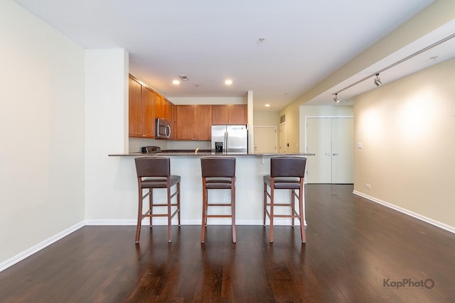 915 S Oak Park Ave Unit 1B, Oak Park, IL 60304 - kitchen with appliances with stainless steel finishes, brown cabinetry, a peninsula, dark wood-type flooring, and a breakfast bar