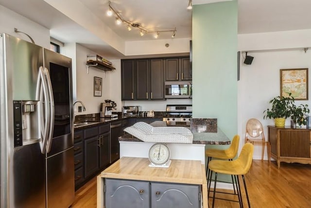 3232 N Halsted St Unit D412, Chicago, IL 60657 - kitchen with stainless steel appliances, light wood-type flooring, a breakfast bar, and dark stone countertops
