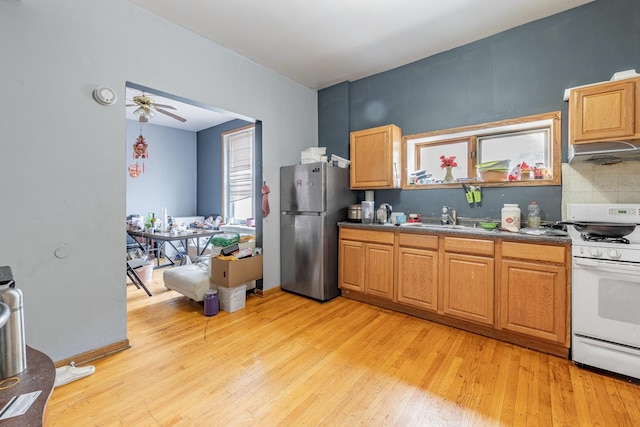 2958 S Lowe Ave, Chicago, IL 60616 - kitchen featuring freestanding refrigerator, white range with gas cooktop, under cabinet range hood, light wood-type flooring, and decorative backsplash
