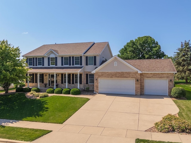 605 Ironwood Cc Dr, Normal, IL 61761 - colonial inspired home with an attached garage, concrete driveway, a front yard, covered porch, and brick siding