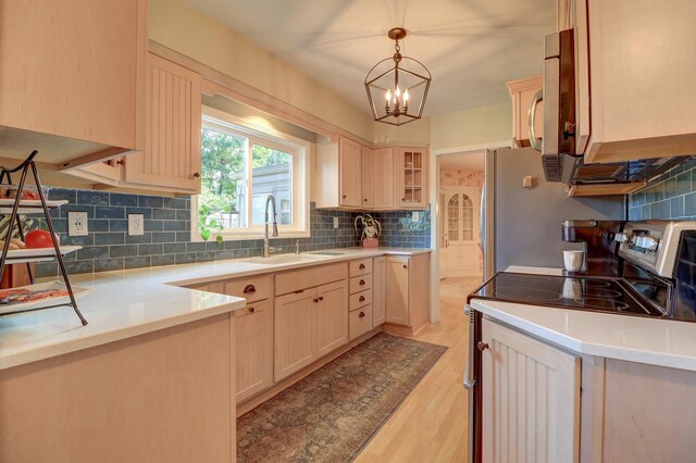 410 W 12th St, Sterling, IL 61081 - kitchen with stainless steel range with electric cooktop, decorative backsplash, light wood finished floors, light countertops, and hanging light fixtures