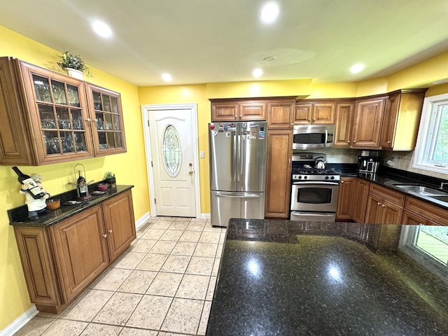 26575 N Fairfield Rd, Wauconda, IL 60084 - kitchen with appliances with stainless steel finishes, glass insert cabinets, brown cabinets, tasteful backsplash, and dark stone counters