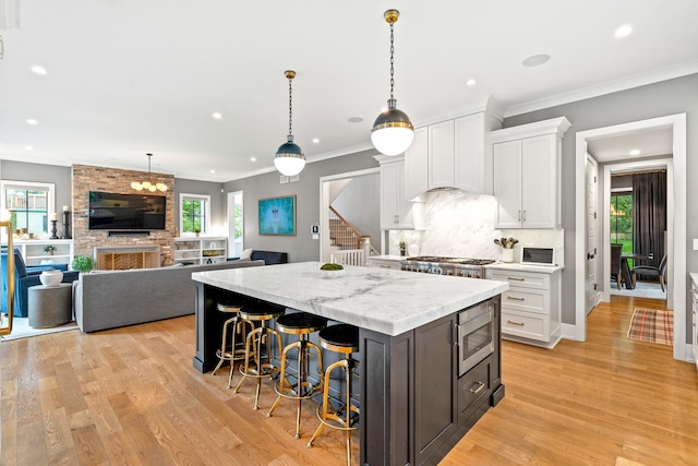 125 S Madison St, Hinsdale, IL 60521 - kitchen with a kitchen island, white cabinets, appliances with stainless steel finishes, light wood-type flooring, and a breakfast bar