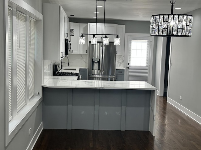 5426 N Bernard St, Chicago, IL 60625 - kitchen with stainless steel fridge, a peninsula, range with gas cooktop, light stone countertops, and backsplash