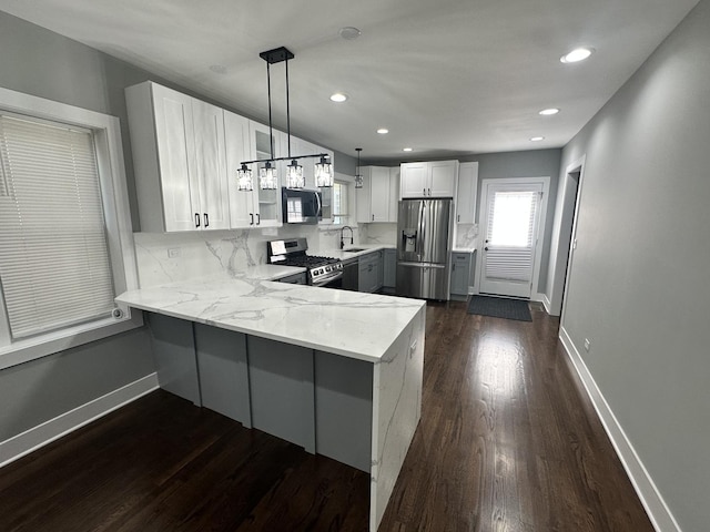 5426 N Bernard St, Chicago, IL 60625 - kitchen with appliances with stainless steel finishes, a peninsula, light stone counters, dark wood-style flooring, and white cabinetry