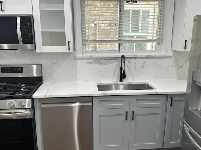 5426 N Bernard St, Chicago, IL 60625 - kitchen with stainless steel appliances, decorative backsplash, light stone counters, glass insert cabinets, and gray cabinets