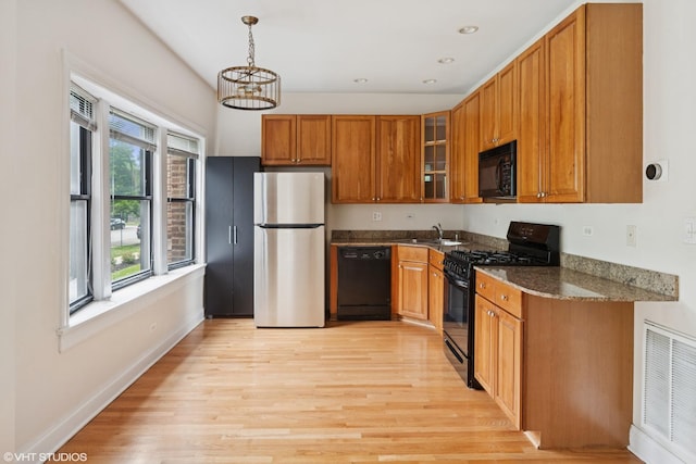4023 N Southport Ave Unit 1, Chicago, IL 60613 - kitchen with black appliances, light wood-style floors, brown cabinets, glass insert cabinets, and dark stone countertops
