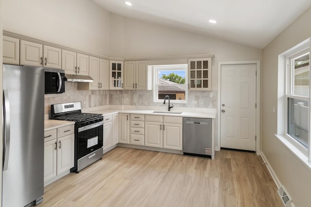 2637 W 93rd Pl, Evergreen Park, IL 60805 - kitchen featuring appliances with stainless steel finishes, vaulted ceiling, under cabinet range hood, decorative backsplash, and light countertops