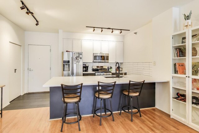 330 N Jefferson St Unit 903, Chicago, IL 60661 - kitchen with appliances with stainless steel finishes, rail lighting, a peninsula, and light wood-type flooring