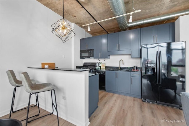 1550 S Blue Island Ave Unit 822, Chicago, IL 60608 - kitchen with black appliances, dark countertops, light wood-style floors, and a breakfast bar