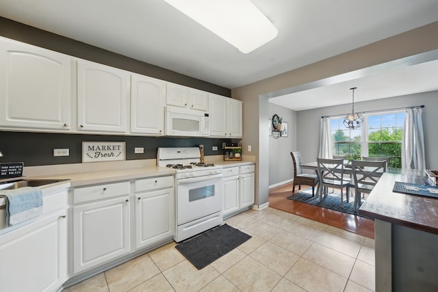 10582 Scott Dr, Huntley, IL 60142 - kitchen featuring white appliances, white cabinetry, pendant lighting, light tile patterned floors, and a chandelier