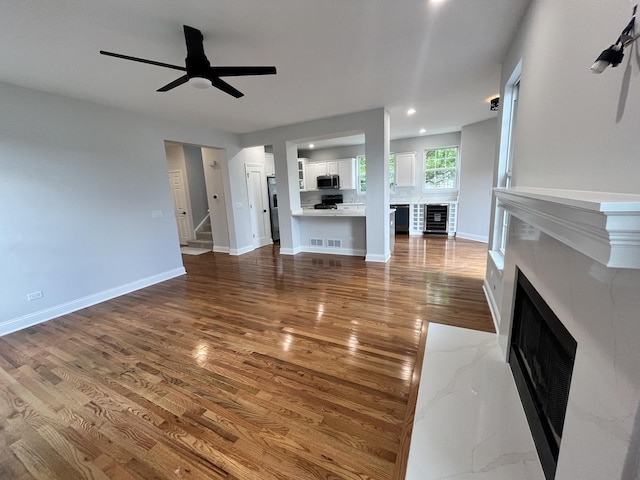 1266 Airs Ave, Sugar Grove, IL 60554 - unfurnished living room featuring wood finished floors, a fireplace, wine cooler, stairs, and ceiling fan