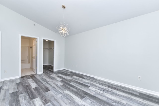 128 Bertram Dr Unit M, Yorkville, IL 60560 - unfurnished bedroom with a chandelier, wood finished floors, a walk in closet, vaulted ceiling, and a closet