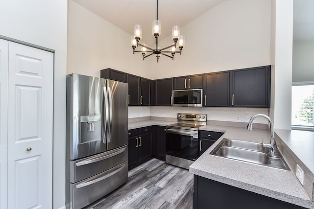 128 Bertram Dr Unit M, Yorkville, IL 60560 - kitchen with stainless steel appliances, light countertops, a chandelier, light wood-type flooring, and a high ceiling