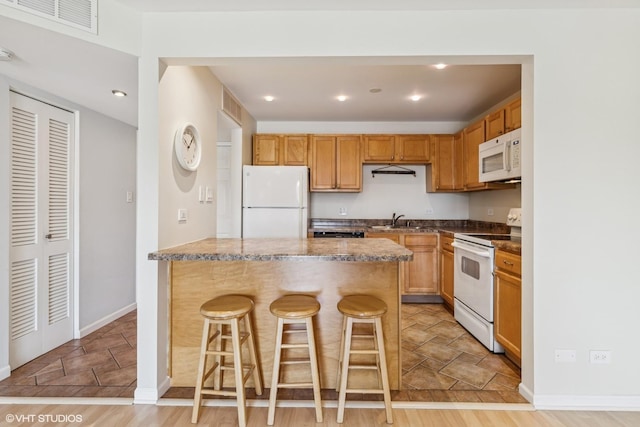 910 Beau Dr Unit 211, Des Plaines, IL 60016 - kitchen with white appliances, stone tile floors, a kitchen breakfast bar, a peninsula, and recessed lighting
