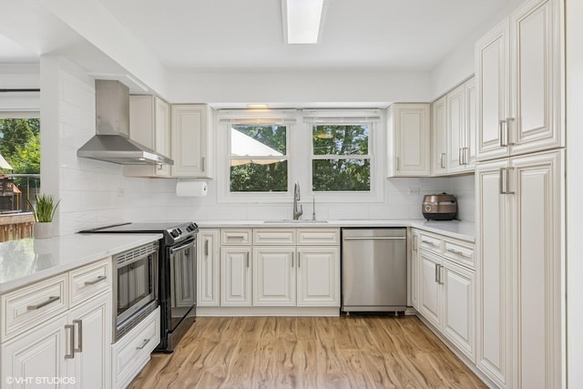 4315 Lombardy Ln, Hoffman Estates, IL 60192 - kitchen featuring appliances with stainless steel finishes, wall chimney range hood, decorative backsplash, light wood-style flooring, and white cabinetry