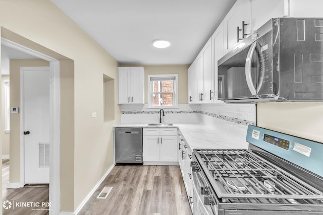 9613 S Yale Ave, Chicago, IL 60628 - kitchen featuring appliances with stainless steel finishes, light wood-style floors, decorative backsplash, and white cabinets