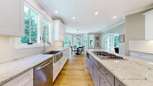 905 Burnham Ct, Aurora, IL 60502 - kitchen featuring stainless steel appliances, white cabinets, decorative backsplash, crown molding, and light stone counters