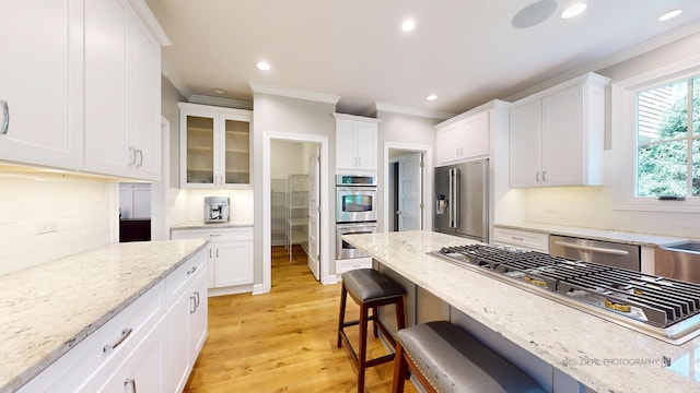 905 Burnham Ct, Aurora, IL 60502 - kitchen with stainless steel appliances, crown molding, white cabinetry, a kitchen bar, and backsplash
