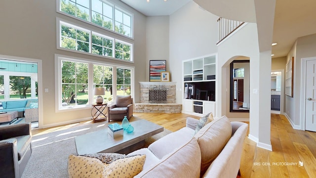 905 Burnham Ct, Aurora, IL 60502 - living room featuring a towering ceiling, a fireplace, light wood-style flooring, and plenty of natural light
