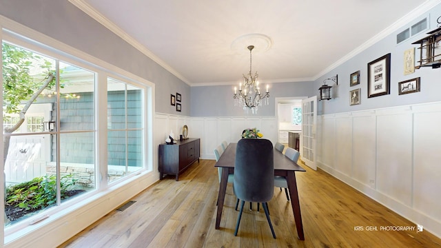 905 Burnham Ct, Aurora, IL 60502 - dining room with a chandelier, light wood-type flooring, ornamental molding, a decorative wall, and wainscoting