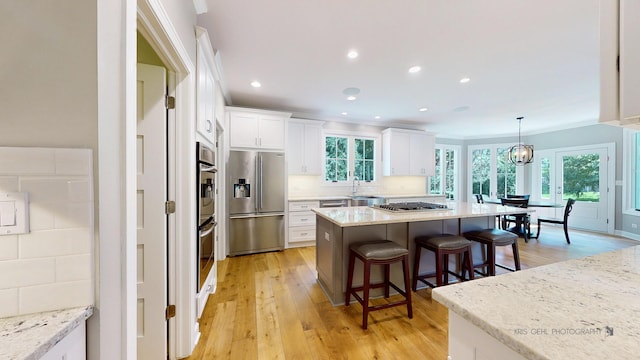 905 Burnham Ct, Aurora, IL 60502 - kitchen with appliances with stainless steel finishes, a kitchen bar, white cabinetry, a kitchen island, and light wood-type flooring