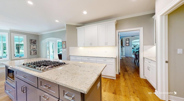 905 Burnham Ct, Aurora, IL 60502 - kitchen featuring appliances with stainless steel finishes, arched walkways, crown molding, white cabinets, and light wood-style floors