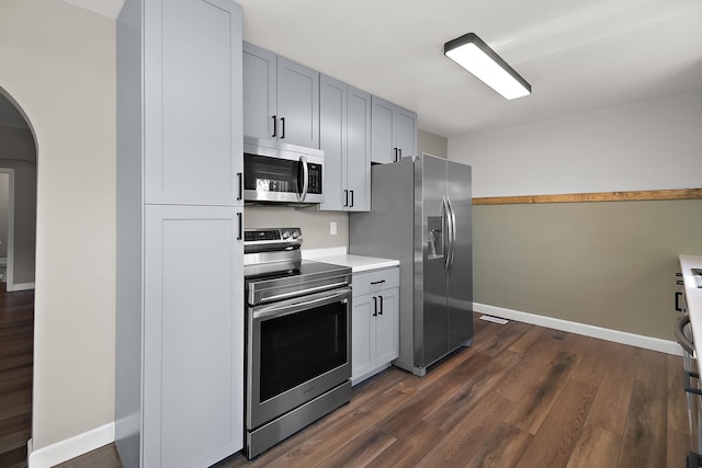 214 S Hickory St, Manteno, IL 60950 - kitchen with appliances with stainless steel finishes, arched walkways, light countertops, dark wood-type flooring, and gray cabinetry