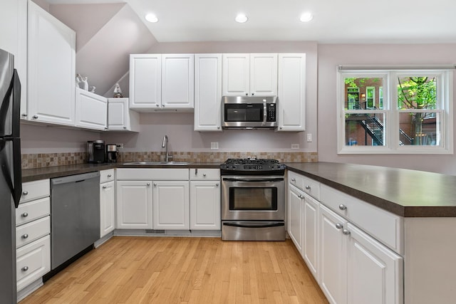 2809 N Wolcott Ave Unit H, Chicago, IL 60657 - kitchen with appliances with stainless steel finishes, dark countertops, a peninsula, light wood-style flooring, and recessed lighting