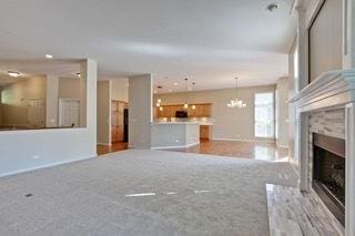 3942 Honeymoon Rdg, Lake In The Hills, IL 60156 - unfurnished living room featuring a fireplace with flush hearth, a chandelier, and carpet