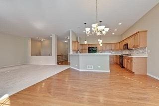 3942 Honeymoon Rdg, Lake In The Hills, IL 60156 - kitchen featuring a chandelier, range with electric stovetop, light wood finished floors, hanging light fixtures, and light countertops