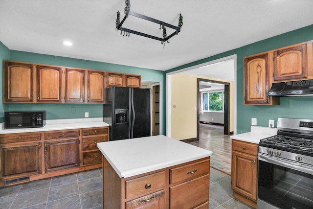 403 E Cooke St, Mount Pulaski, IL 62548 - kitchen featuring black appliances, under cabinet range hood, light countertops, brown cabinets, and a kitchen island