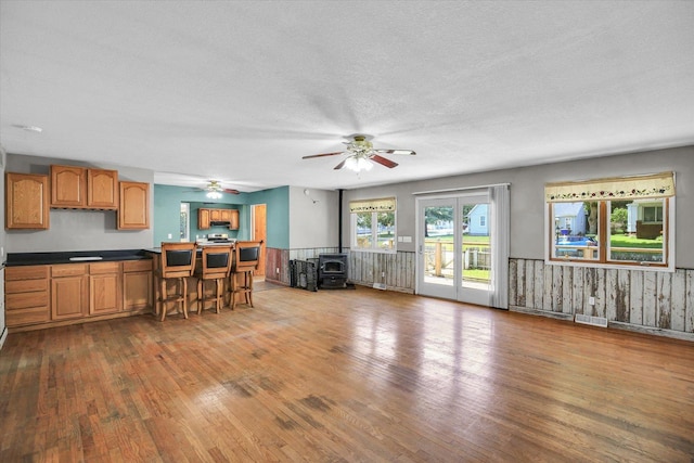 403 E Cooke St, Mount Pulaski, IL 62548 - kitchen with hardwood / wood-style flooring, a wood stove, a ceiling fan, dark countertops, and a textured ceiling