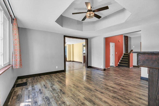 403 E Cooke St, Mount Pulaski, IL 62548 - empty room featuring a raised ceiling, ceiling fan, wood finished floors, and stairway