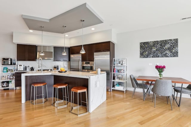 650 N Morgan St Unit 303, Chicago, IL 60642 - kitchen featuring stainless steel appliances, light wood-type flooring, dark brown cabinetry, a breakfast bar, and recessed lighting
