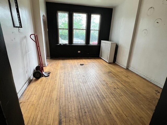 10614 S Langley Ave Unit 10614, Chicago, IL 60628 - empty room featuring light wood finished floors, radiator, and arched walkways
