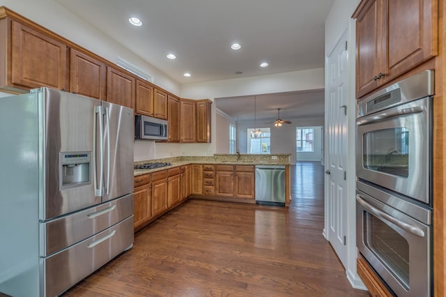 3866 Kingsmill Dr, Elgin, IL 60124 - kitchen featuring appliances with stainless steel finishes, a peninsula, light stone countertops, dark wood-style floors, and recessed lighting