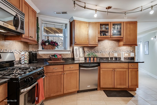 7612 N Rogers Ave Unit G, Chicago, IL 60626 - kitchen featuring stainless steel appliances, dark stone countertops, light tile patterned floors, brown cabinets, and glass insert cabinets