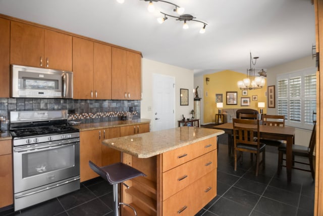 21309 Silktree Cir, Plainfield, IL 60544 - kitchen featuring appliances with stainless steel finishes, dark tile patterned flooring, tasteful backsplash, a kitchen island, and a chandelier