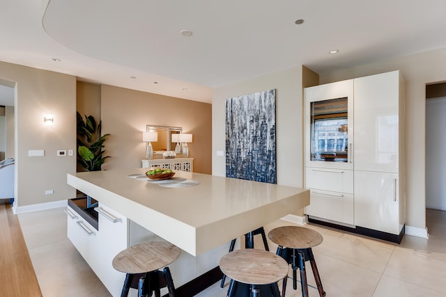 270 E Pearson St Unit 1402, Chicago, IL 60611 - kitchen featuring a kitchen breakfast bar, white cabinets, modern cabinets, light tile patterned floors, and recessed lighting