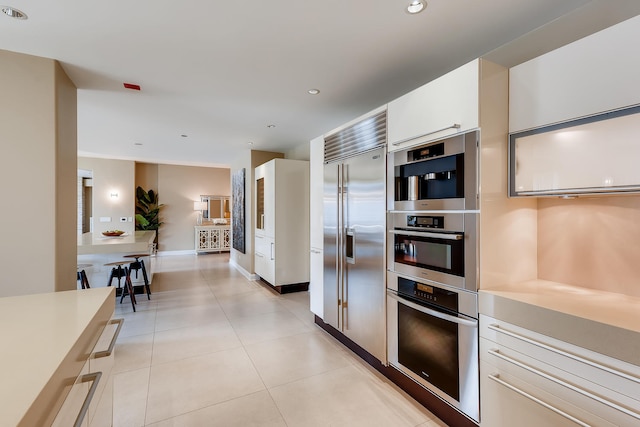 270 E Pearson St Unit 1402, Chicago, IL 60611 - kitchen with stainless steel built in fridge, white cabinets, recessed lighting, light countertops, and light tile patterned floors