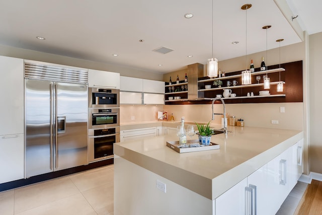 270 E Pearson St Unit 1402, Chicago, IL 60611 - kitchen featuring appliances with stainless steel finishes, open shelves, white cabinets, decorative light fixtures, and light countertops