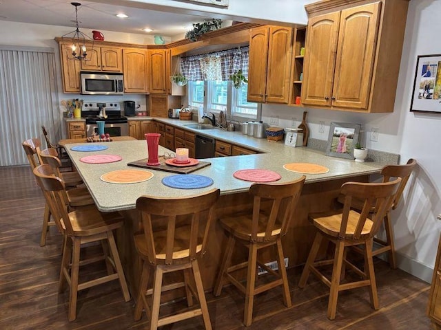 1591 N 2700 E Rd, Sheldon, IL 60966 - kitchen featuring appliances with stainless steel finishes, brown cabinets, light countertops, a peninsula, and hanging light fixtures