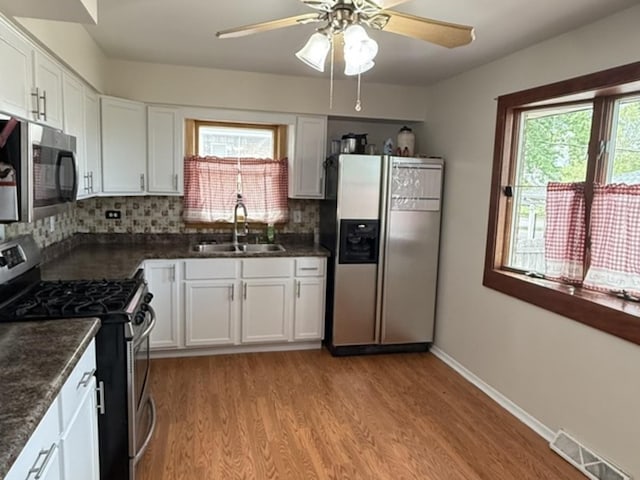 7707 S Oketo Ave, Bridgeview, IL 60455 - kitchen with stainless steel appliances, light wood-style floors, ceiling fan, white cabinets, and backsplash