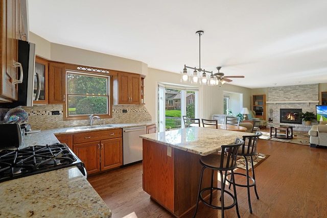 6316 Knollwood Ct, Lisle, IL 60532 - kitchen featuring appliances with stainless steel finishes, a kitchen island, ceiling fan, brown cabinetry, and a kitchen bar