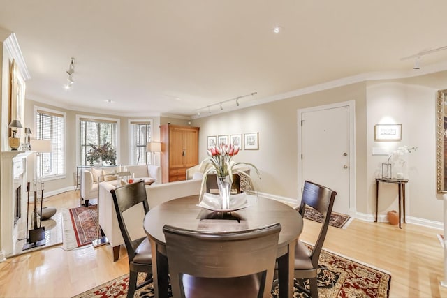 917 W Gunnison St Unit 1W, Chicago, IL 60640 - dining area featuring track lighting, light wood-style flooring, ornamental molding, and a fireplace